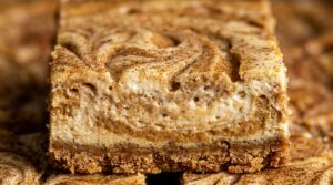 Ultra close-up macro of creamy spiced pumpkin cheesecake bars with golden graham cracker crust and delicate spiced swirl